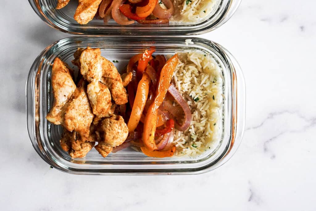 Chicken, vegetables, and rice in glass containers.