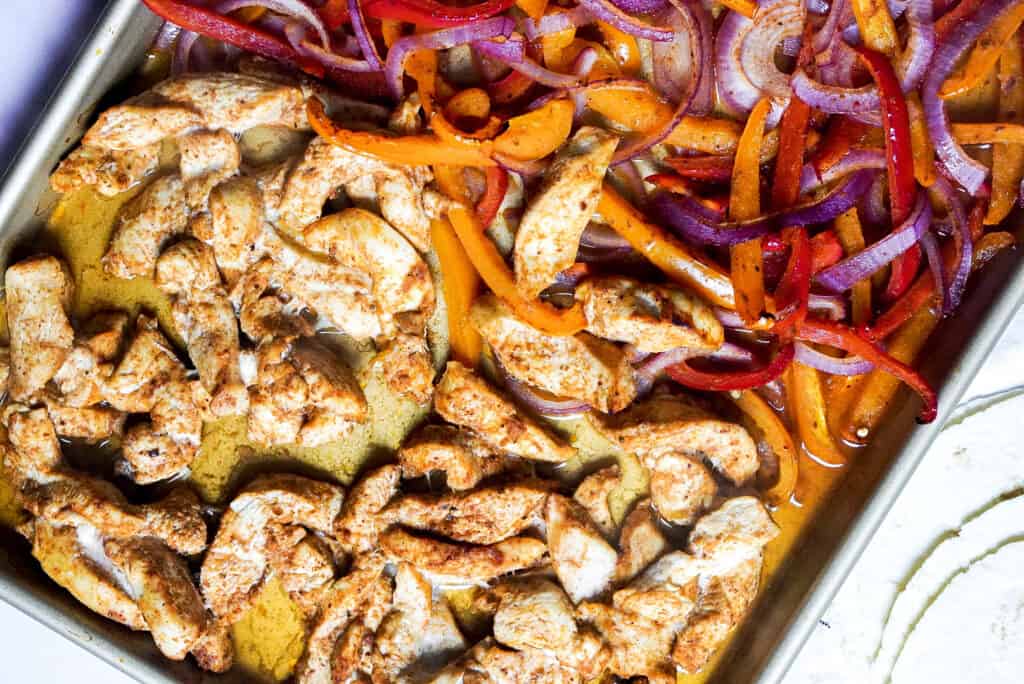 Seasoned chicken and vegetables on a sheet pan.