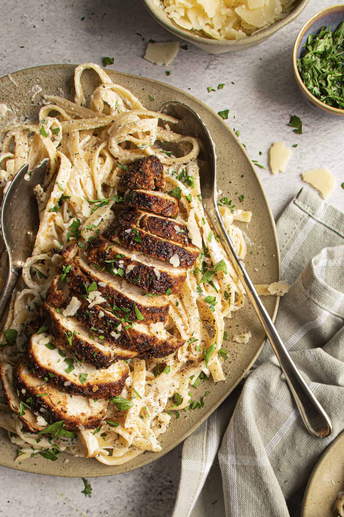 Blackened chicken over pasta with parsley plated to serve. 