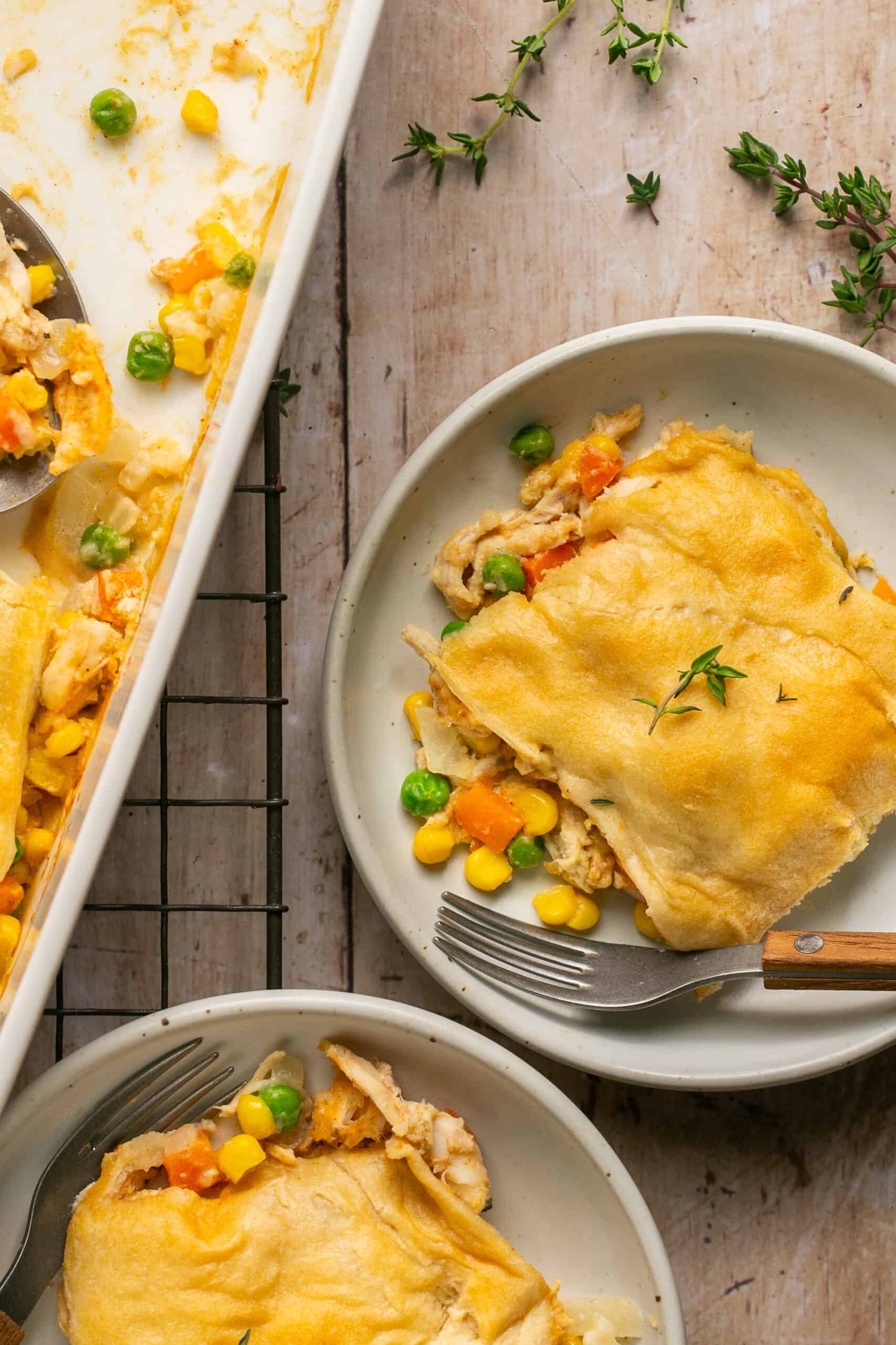 One serving of pot pie on a plate with a fork topped with fresh thyme.