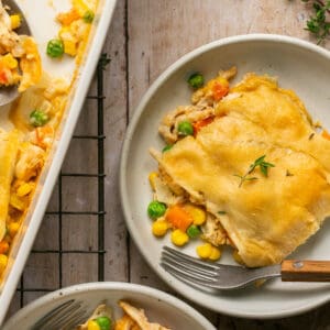 One serving of pot pie on a plate with a fork topped with fresh thyme.