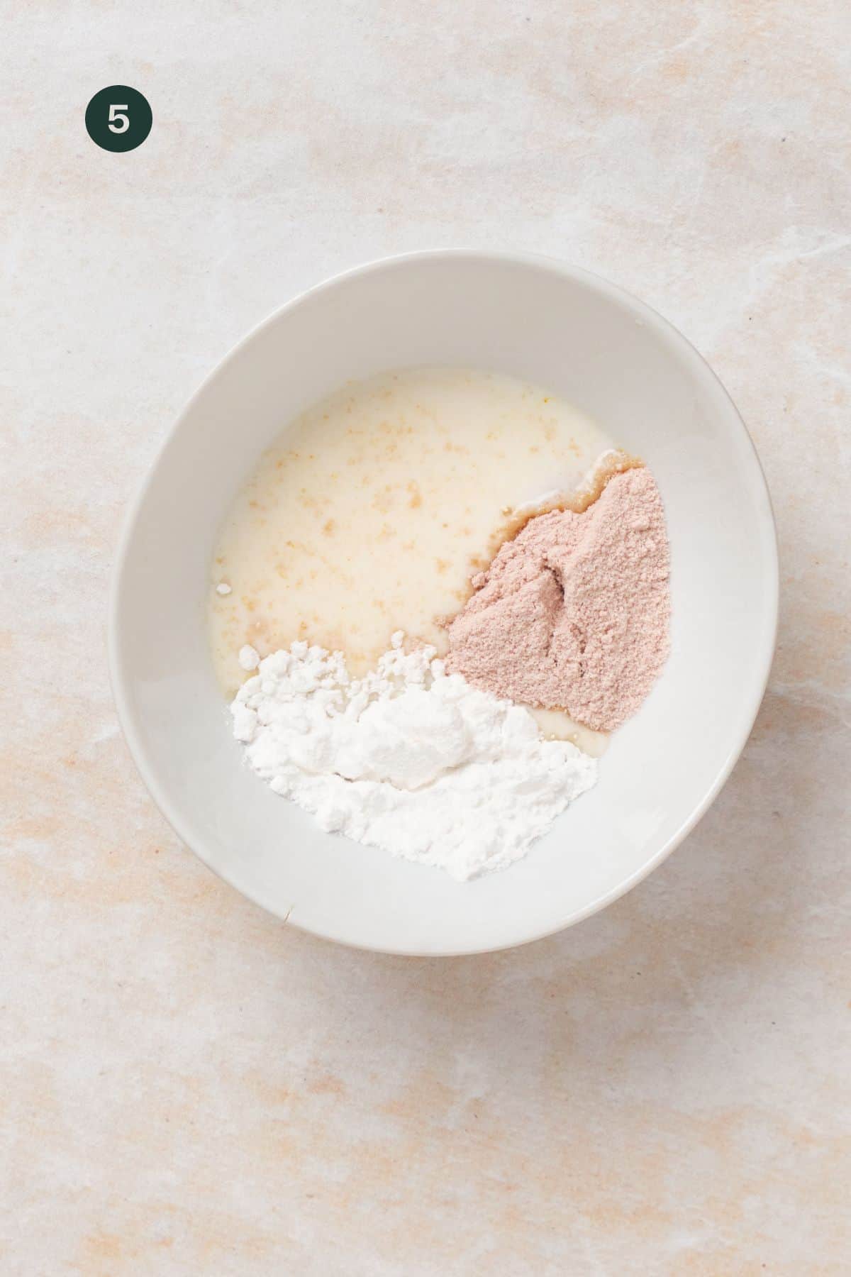 Milk, protein powder and sugar added to a bowl. 