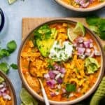 Soup topped with avocado, limes, onions, tortilla strips and cilantro.