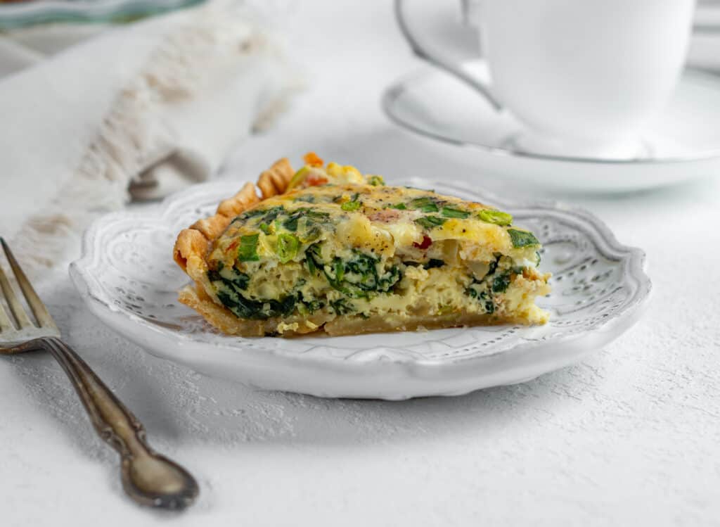 Slice of breakfast quiche on a small plate.