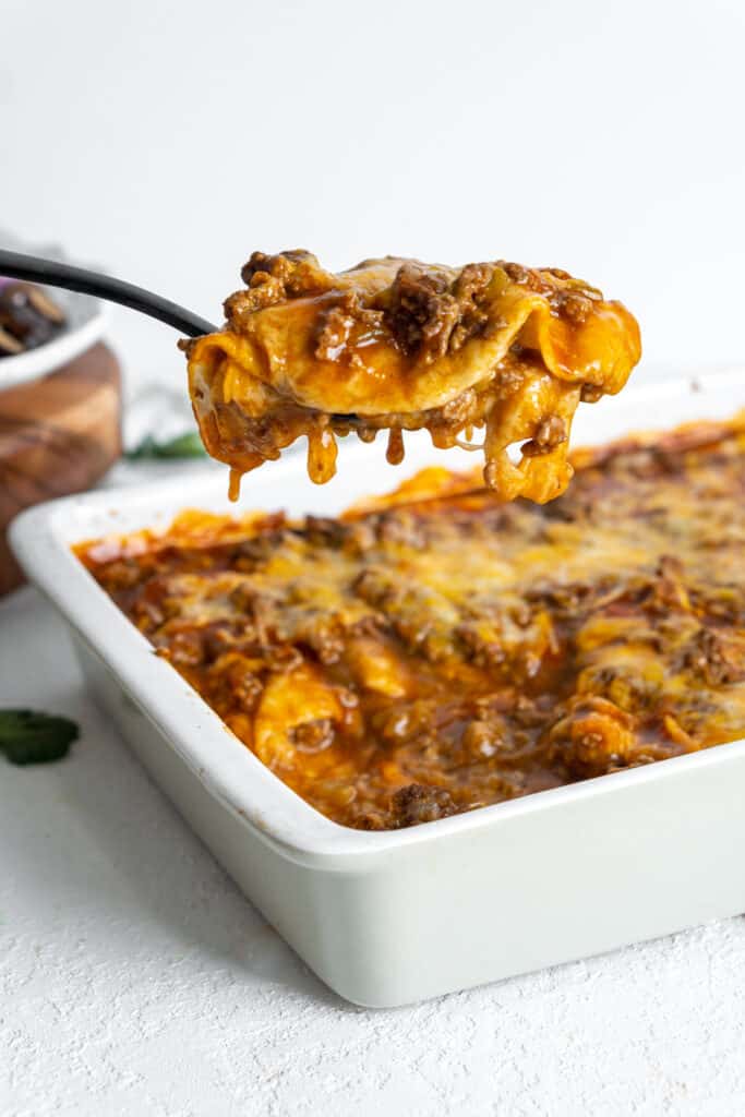 Spatula scooping lazy enchiladas from a baking dish.