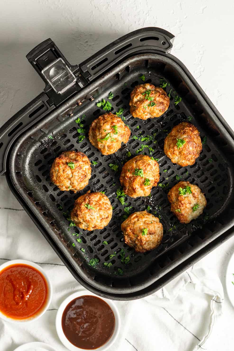 Meatballs in the base of the air fryer basket cooked and browned. 