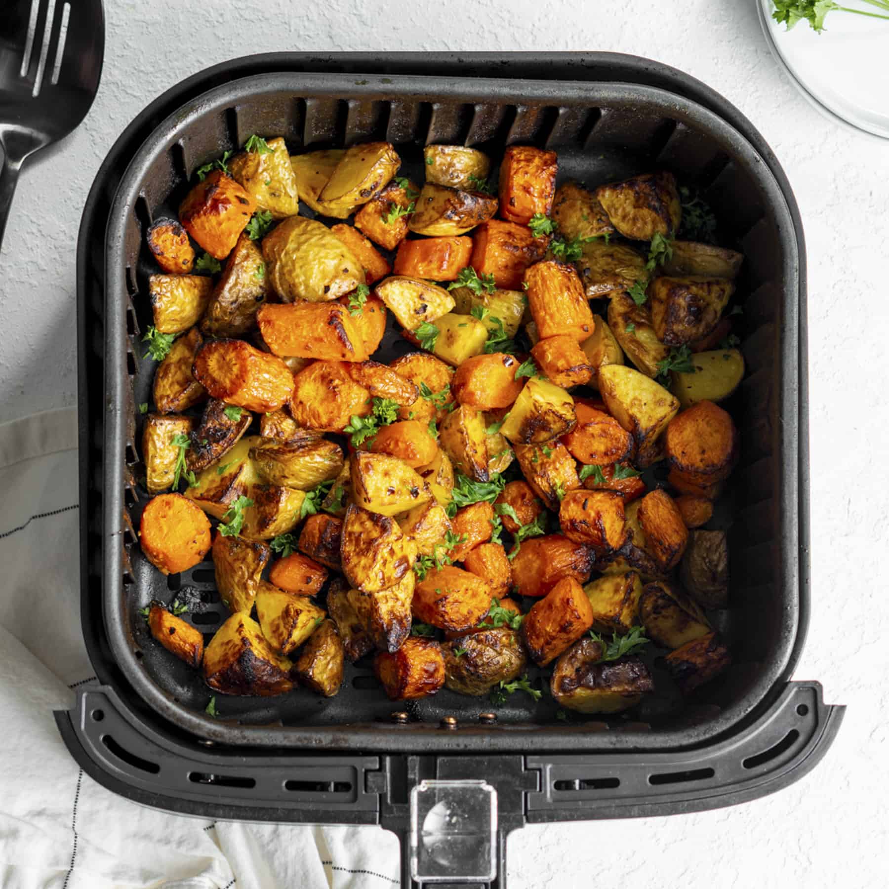 Carrots and potatoes in the air fryer basket cooked.