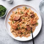 Plated shrimp and sausage pasta with a fork and parsley on top.