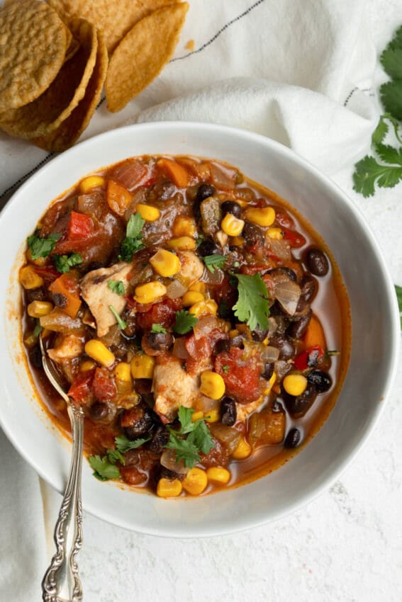 Bowl of black bean chili with chicken, corn and cilantro on top.
