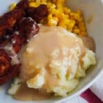 Bowl with mashed potatoes and gravy, chicken, and corn.