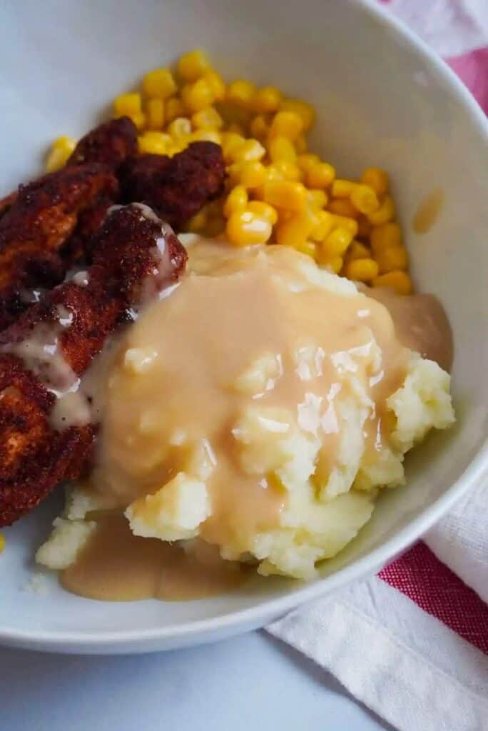 Bowl with mashed potatoes and gravy, chicken, and corn.