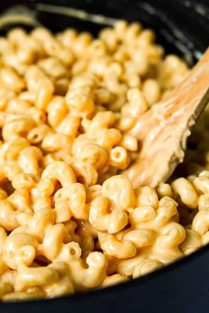 Wooden spatula stirring protein mac and cheese.