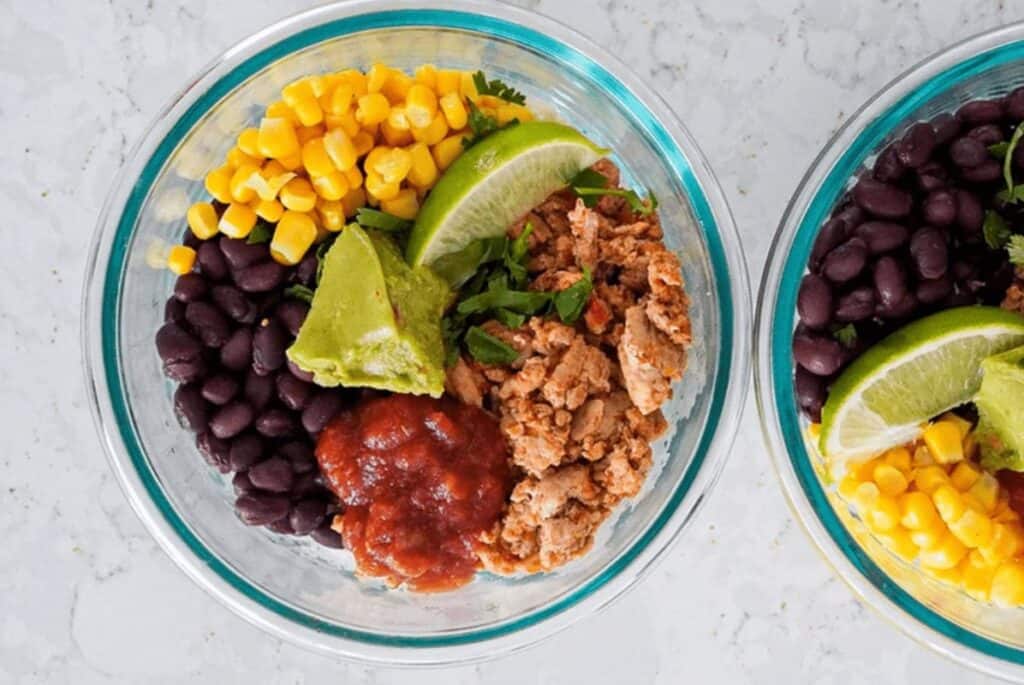 Glass bowls with turkey, salsa, beans, corns, and lime wedges.