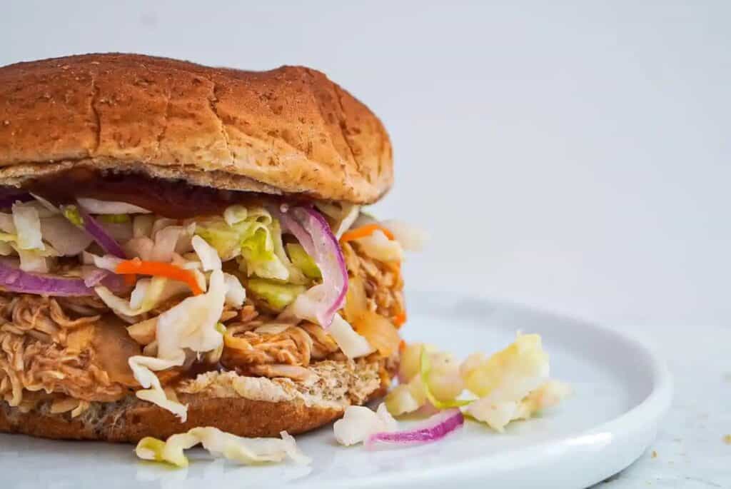 Crockpot barbeque pulled chicken sandwich on a large, white plate.