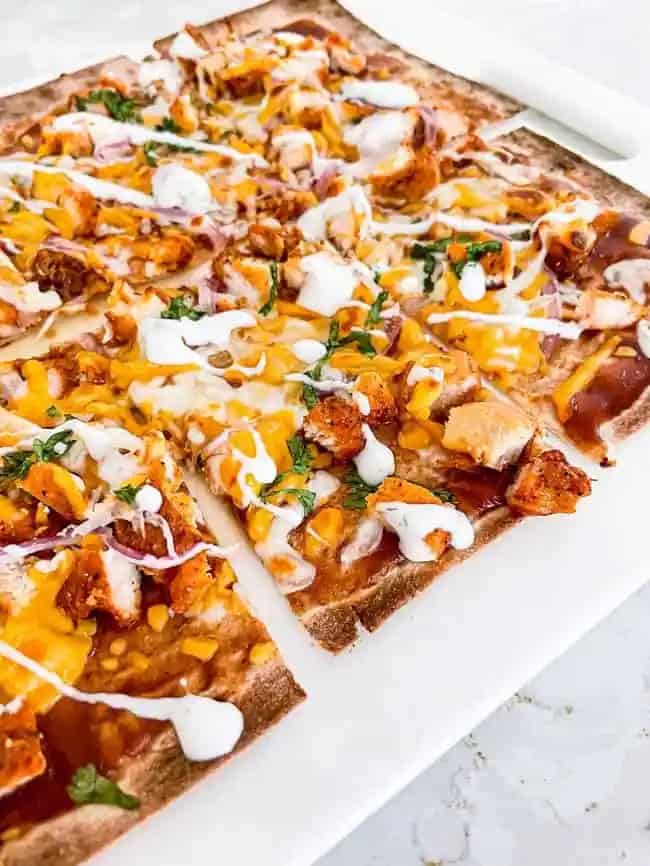 Sliced barbeque chicken pizza on a white plate.