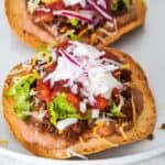 Two beef and bean tostadas on a white plate.