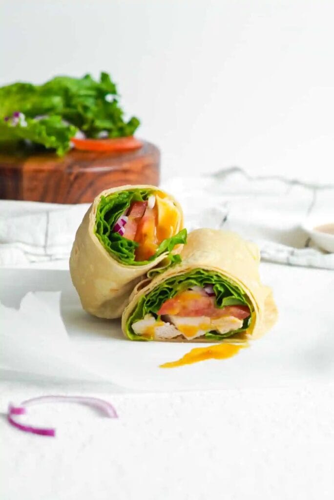 Halved honey mustard chicken wrap on parchment paper.