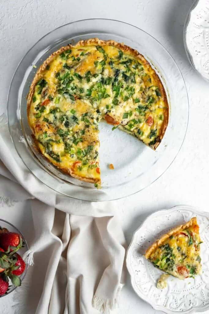 Vegetable quiche on a plate and in a glass pie tin.