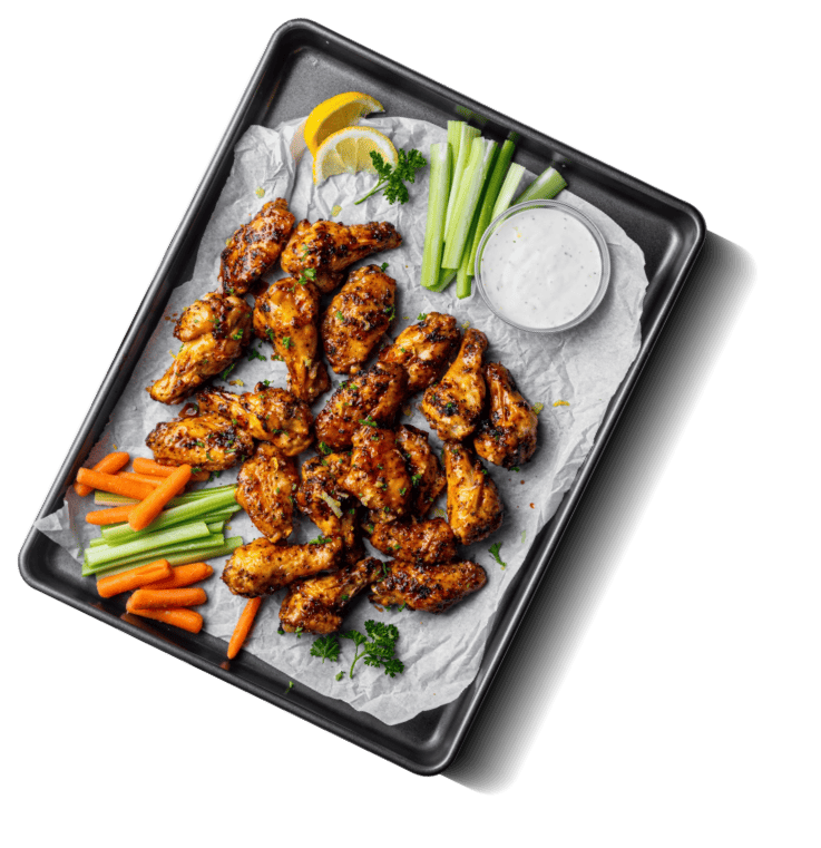 Chicken wings, cut vegetables, and dip on a tray.
