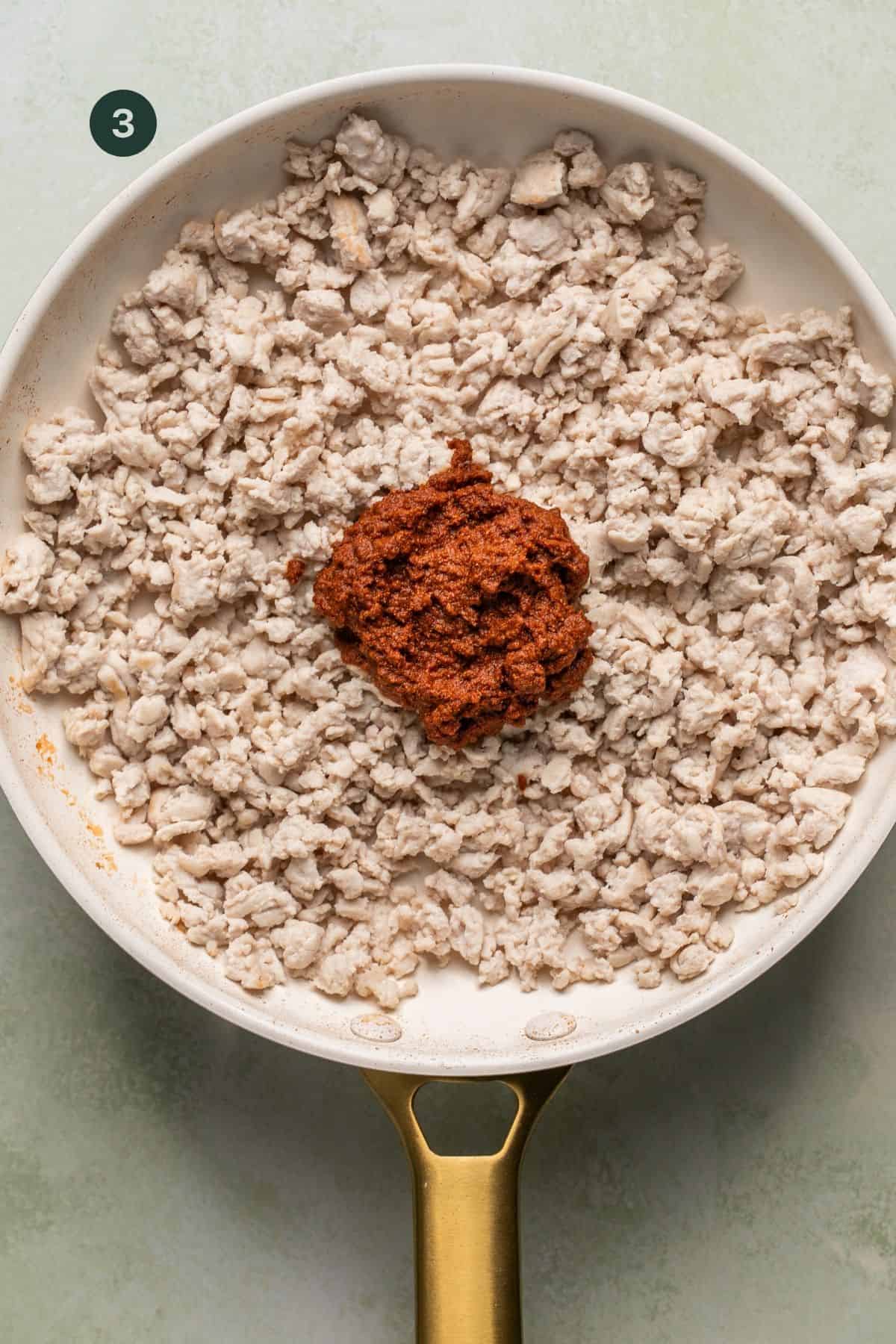 Taco seasoning mixed with water to create a paste, added to ground turkey in a pan.