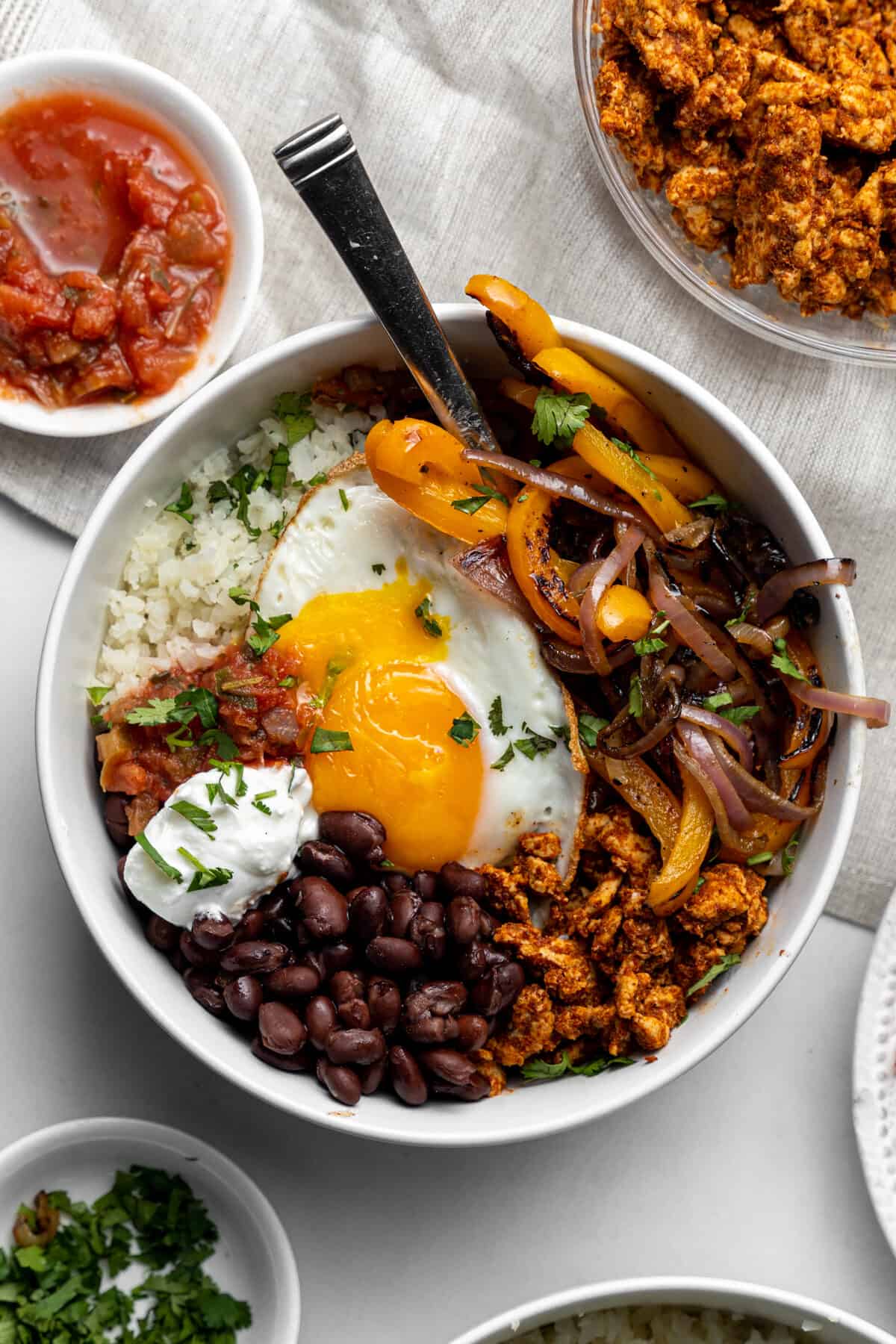 Breakfast burrito bowl with beans, egg, vegetables, and more.
