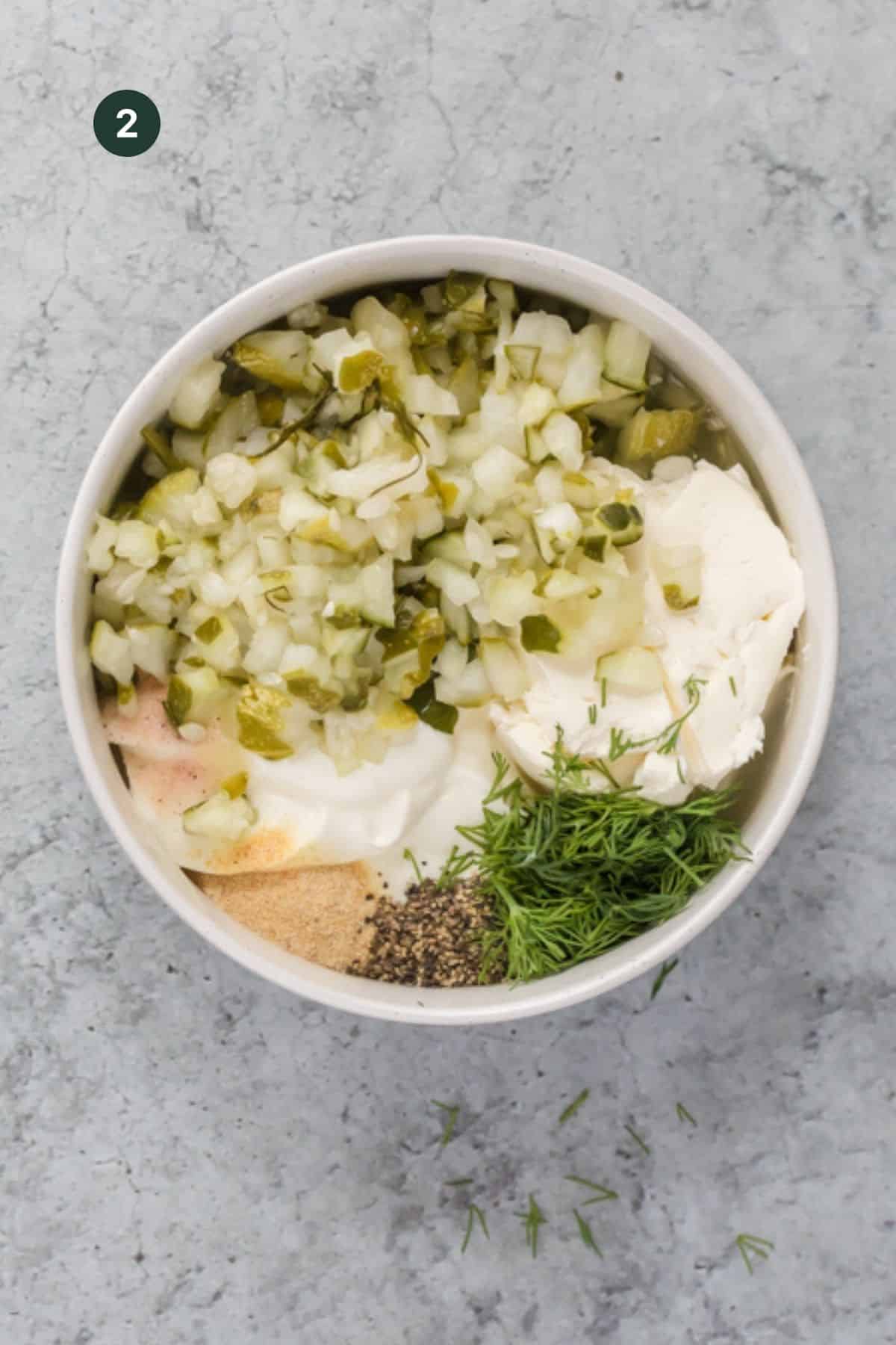 Yogurt, cream cheese, cottage cheese, pickles, pickle juice, salt, pepper, dill and garlic powder added to a bowl to mix. 