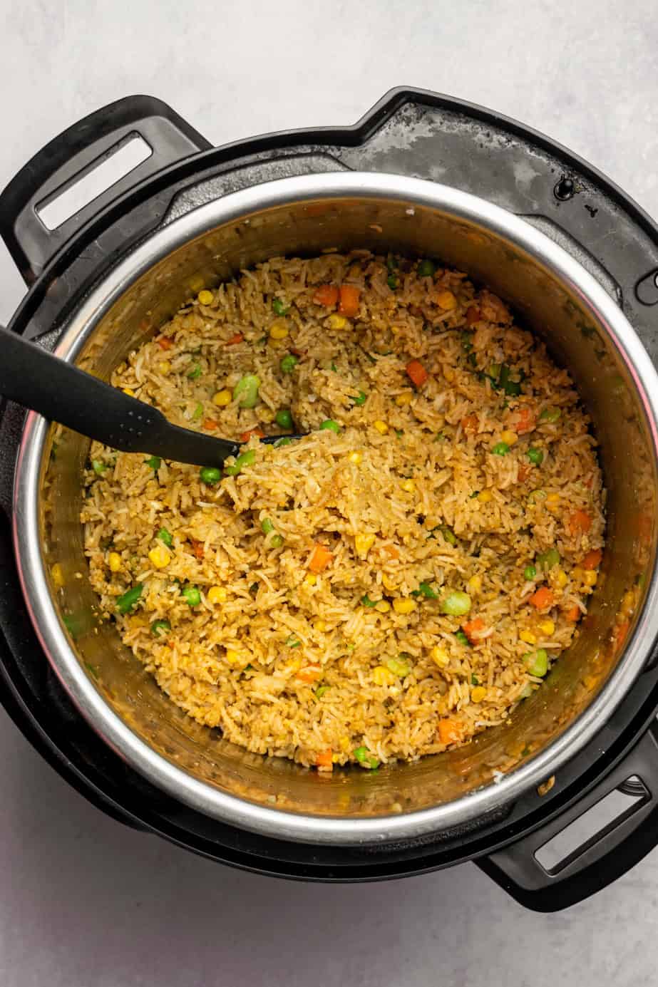 Rice in the base of an instant pot with a spoon to serve. 