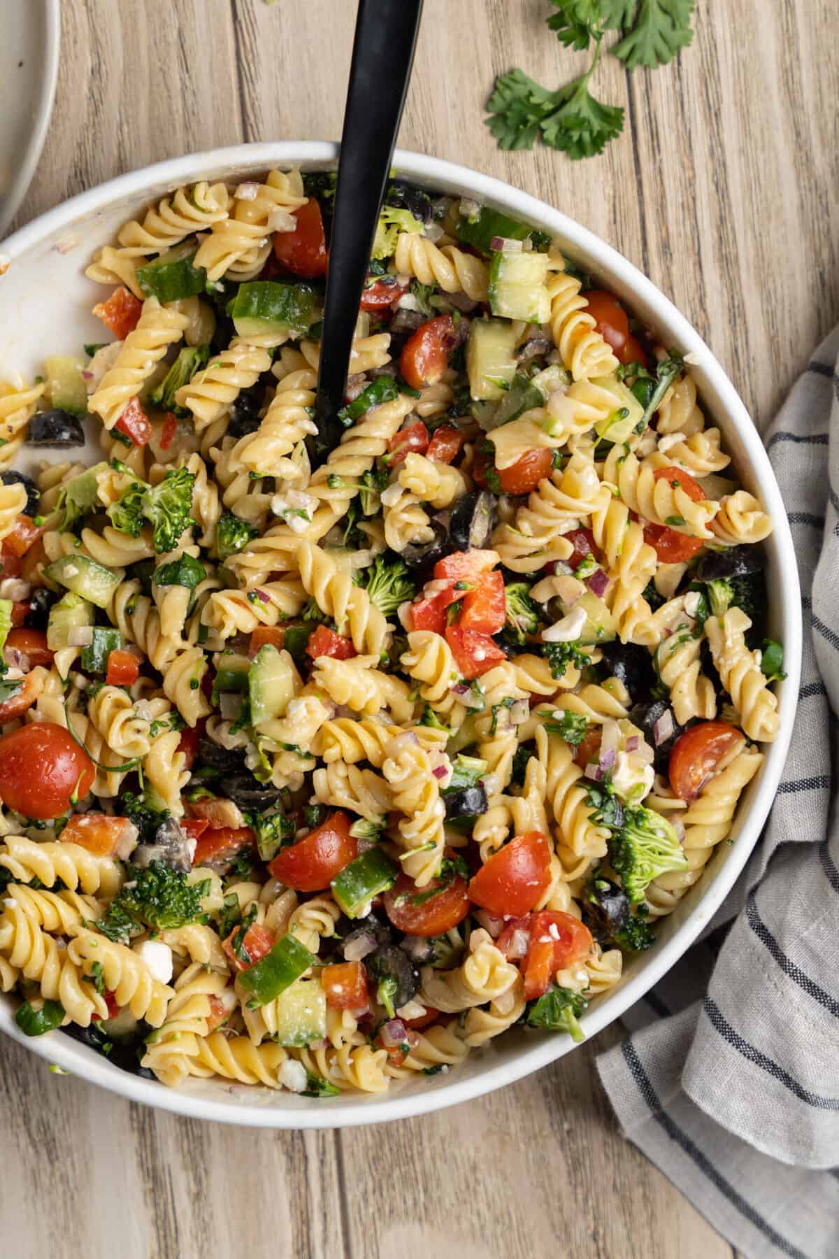 Mixed pasta salad in a bowl with a spoon. 