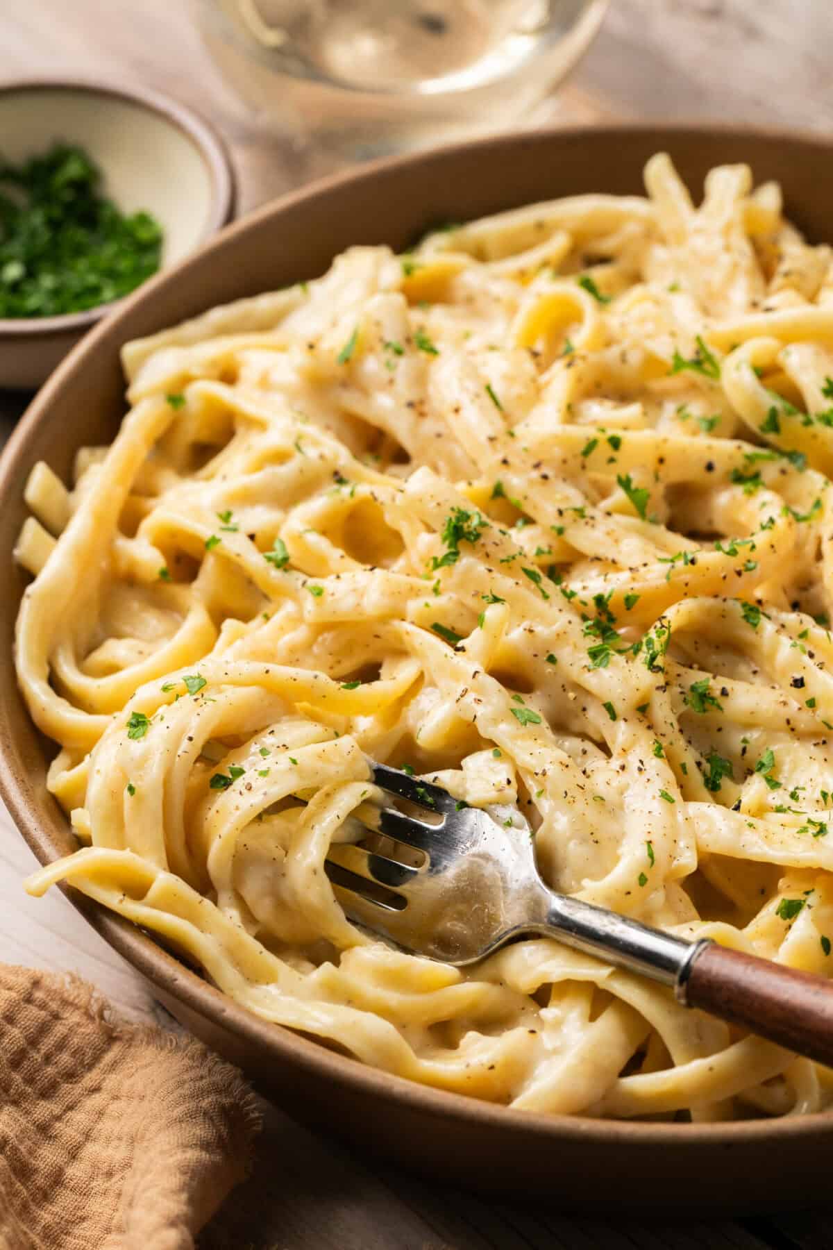 Fork rolled into creamy fettuccine alfredo made in the instant pot in a bowl for serving. 