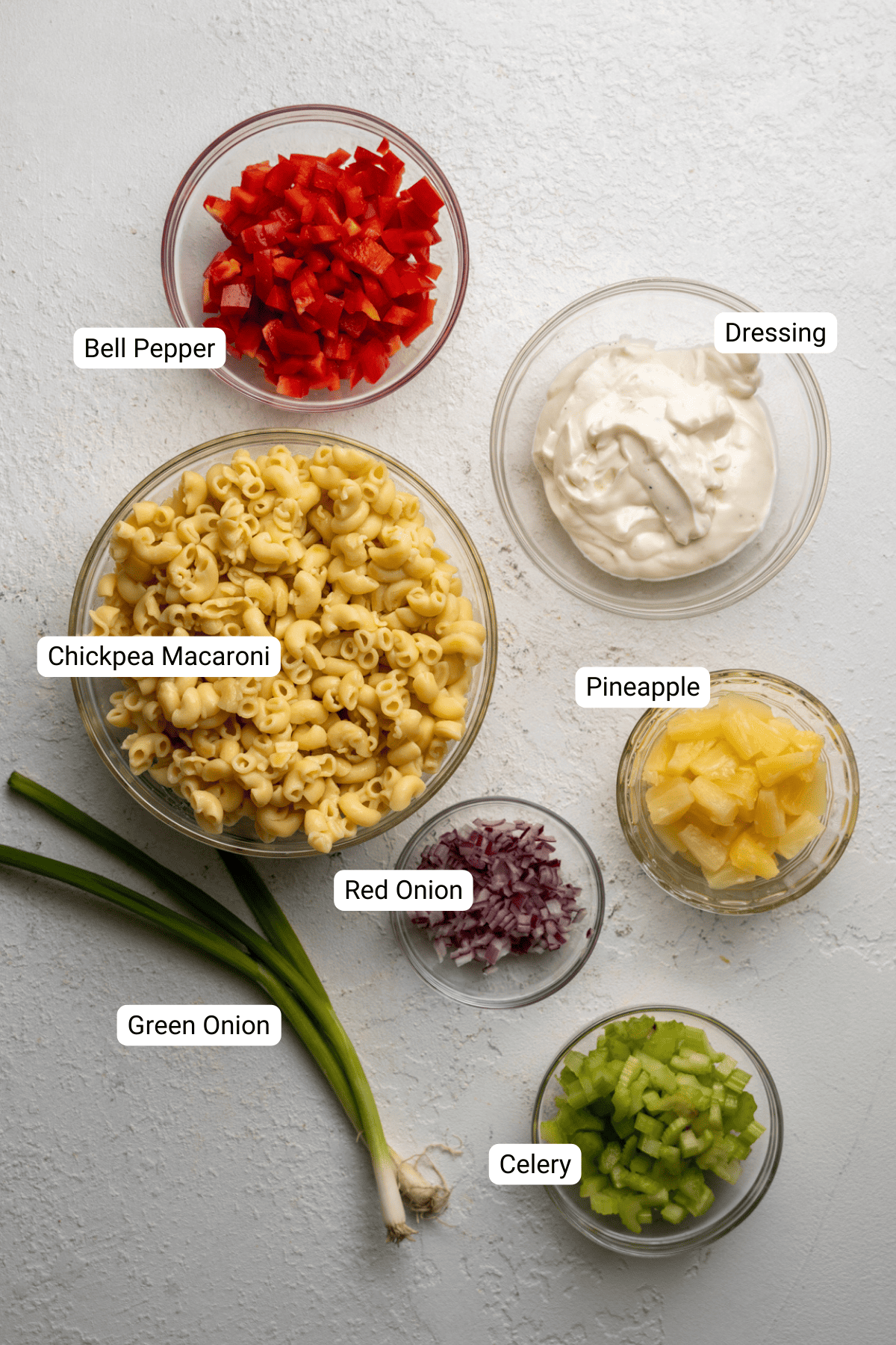 Macaroni salad ingredients including bell pepper, pineapple, and red onion.