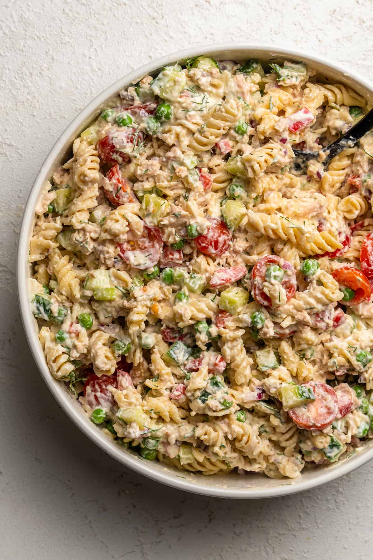Creamy pasta salad in a large mixing bowl full of fresh vegetables and tuna.