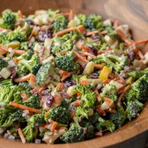 Vegetable packed broccoli salad with a creamy dressing in a wooden serving bowl.