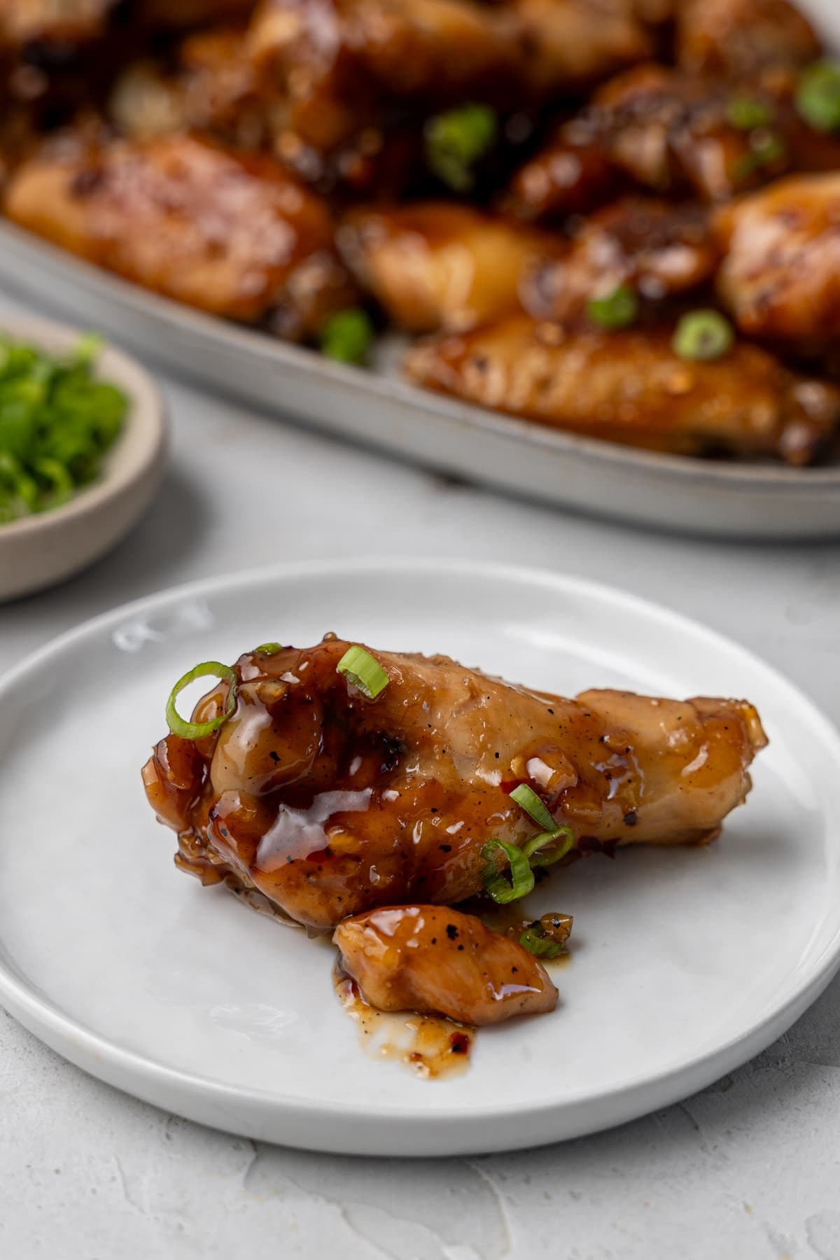 Honey garlic wing on a small plate.