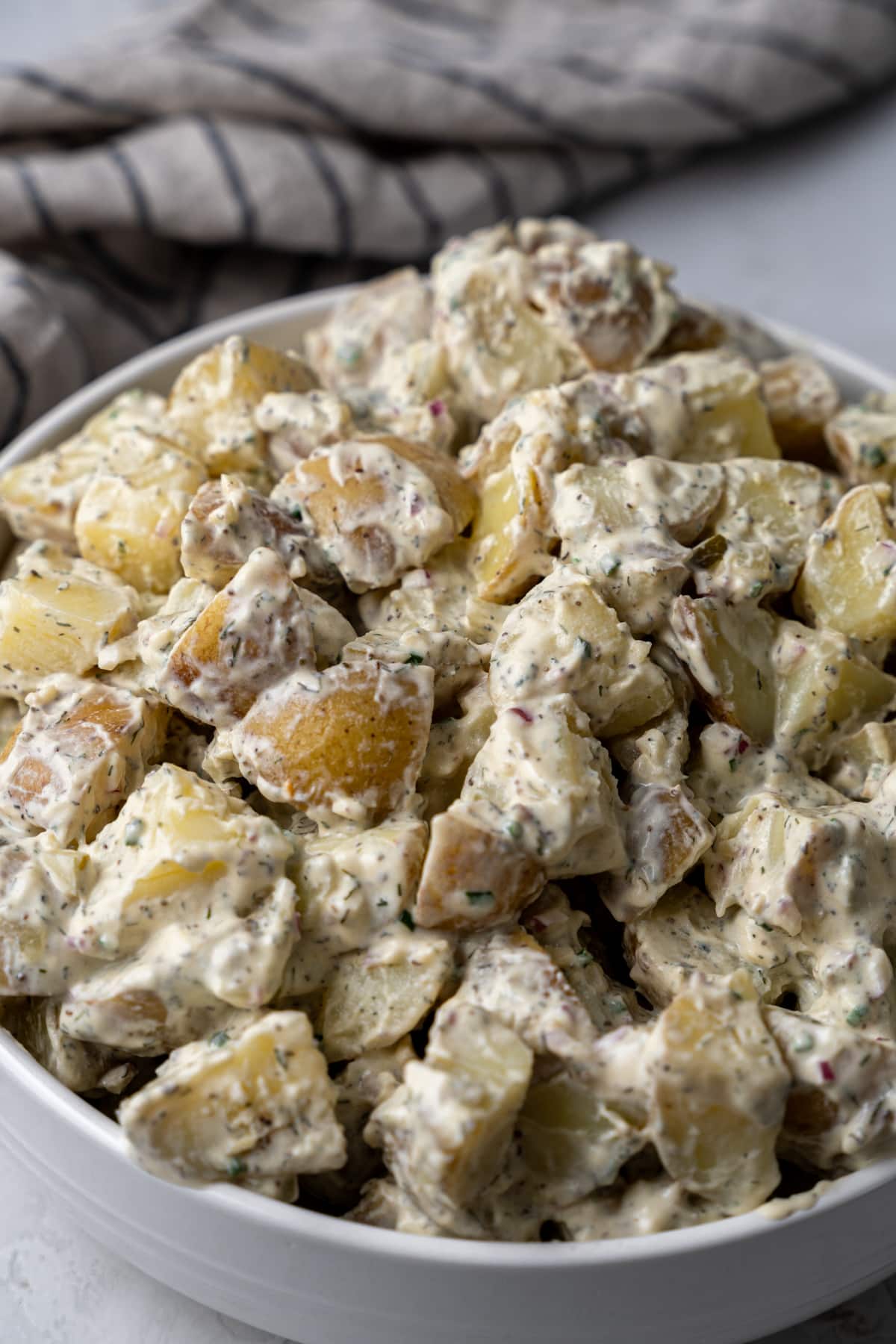 Potato salad piled high in a white bowl.