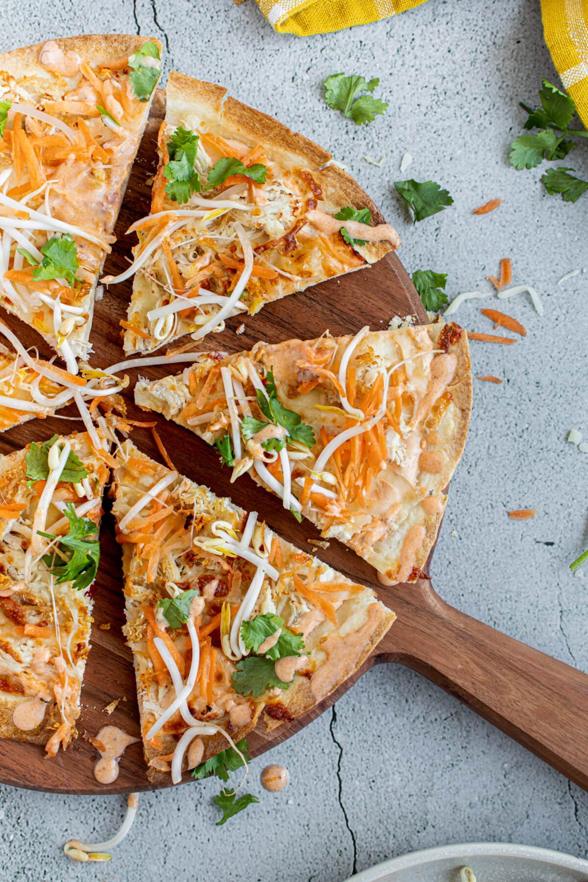 Sliced Thai curry pizza on a wooden pizza board.