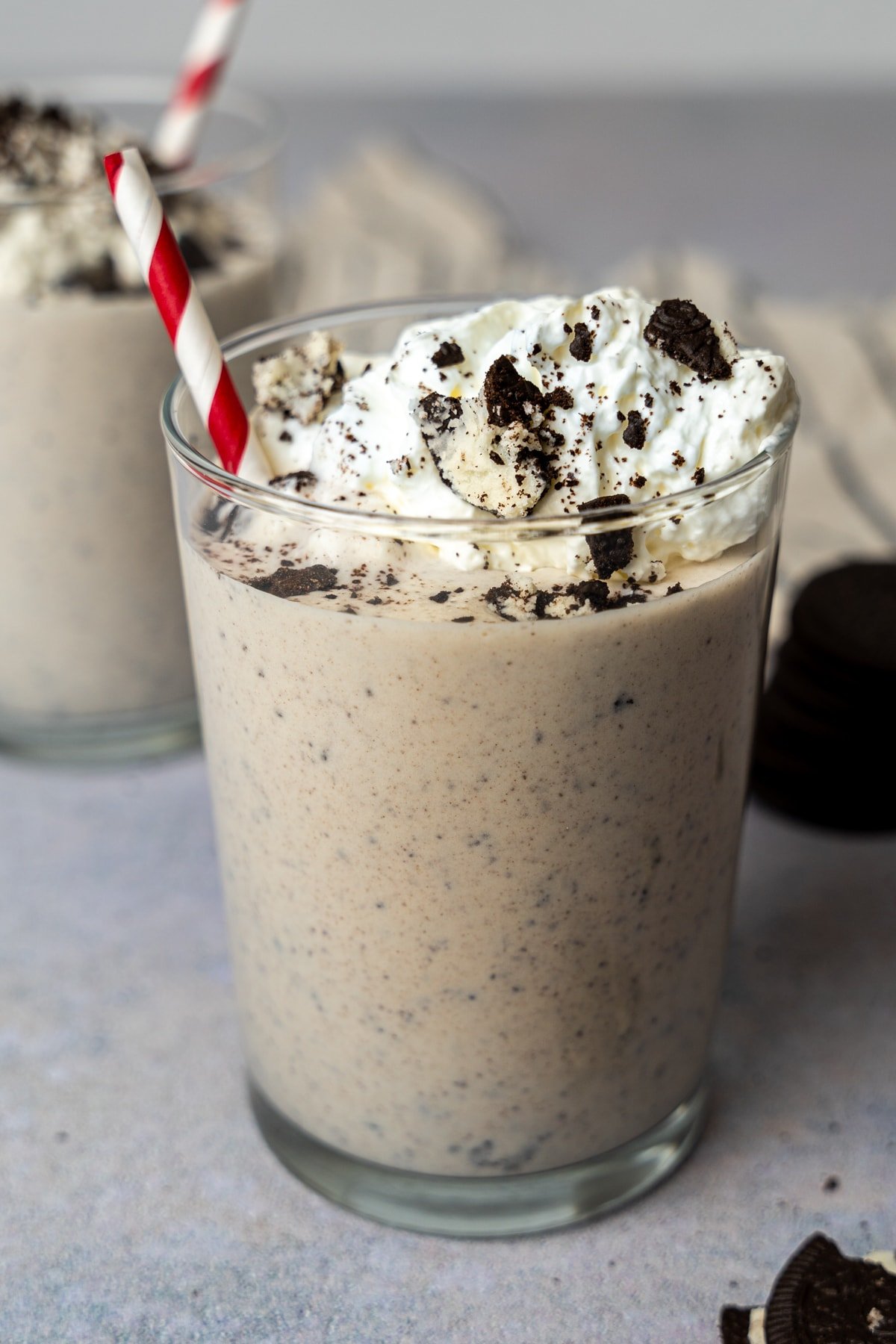 Cookies and cream protein shake with a red and white striped straw.