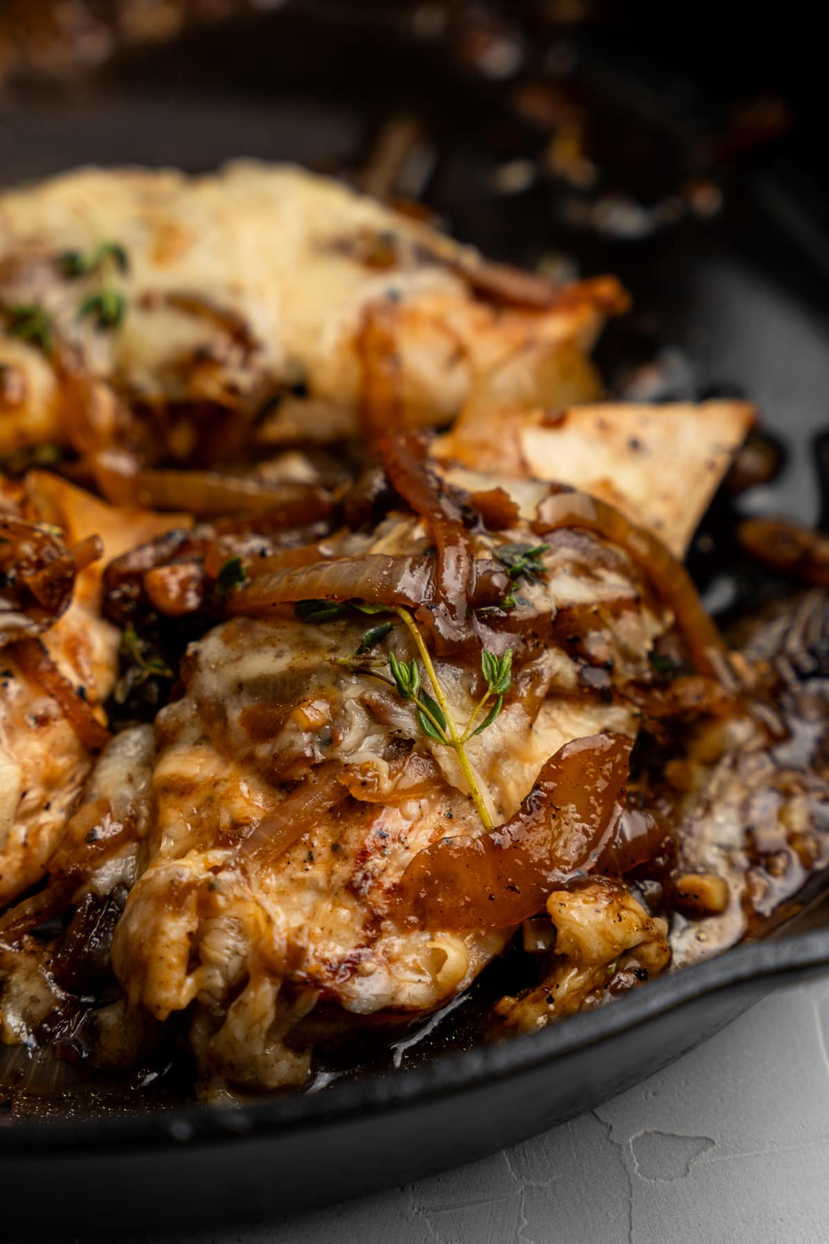 Chicken in a skillet topped with French onion ingredients.