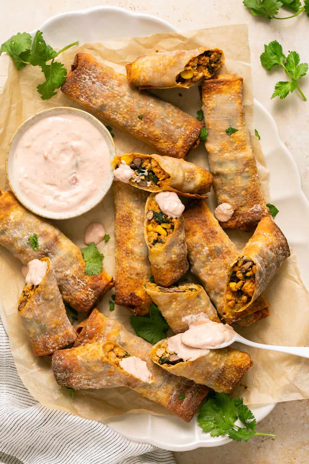 Air fryer southwest egg rolls on a parchment-lined platter with dip.