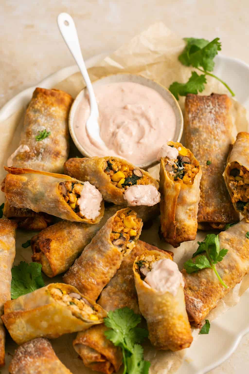 Air fryer southwest egg rolls and creamy salsa sauce on a parchment-lined platter.