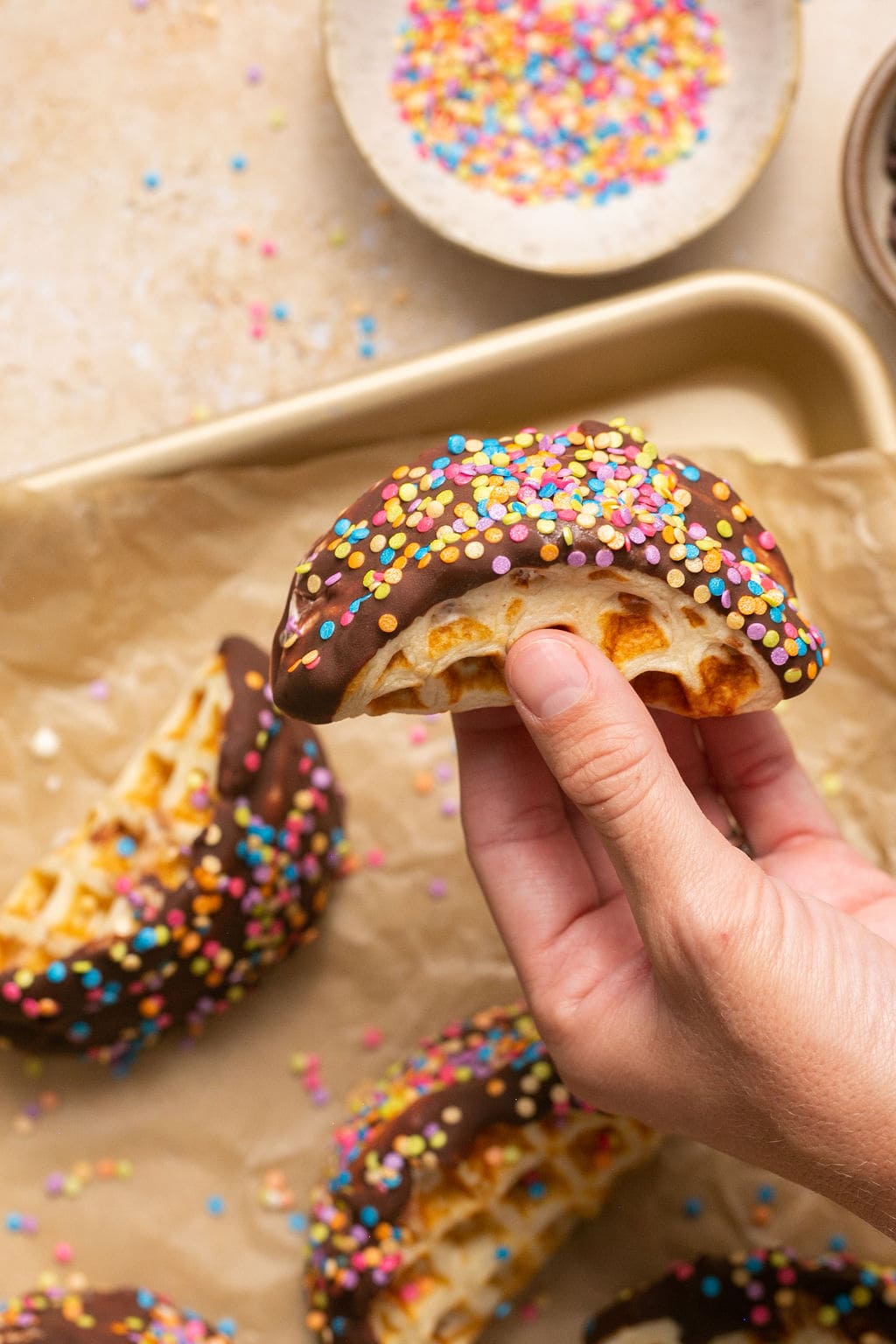 Person holding a homemade Choco taco topped with colorful sprinkles.