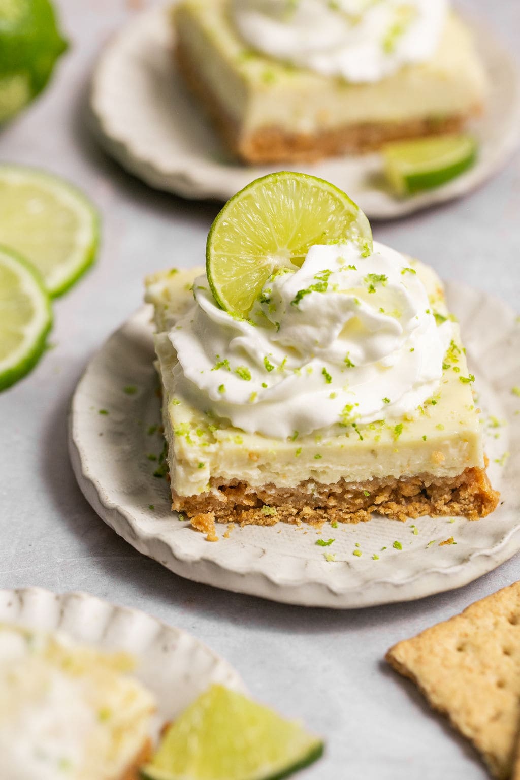 Key lime pie bar topped with a lime slice on a small plate.