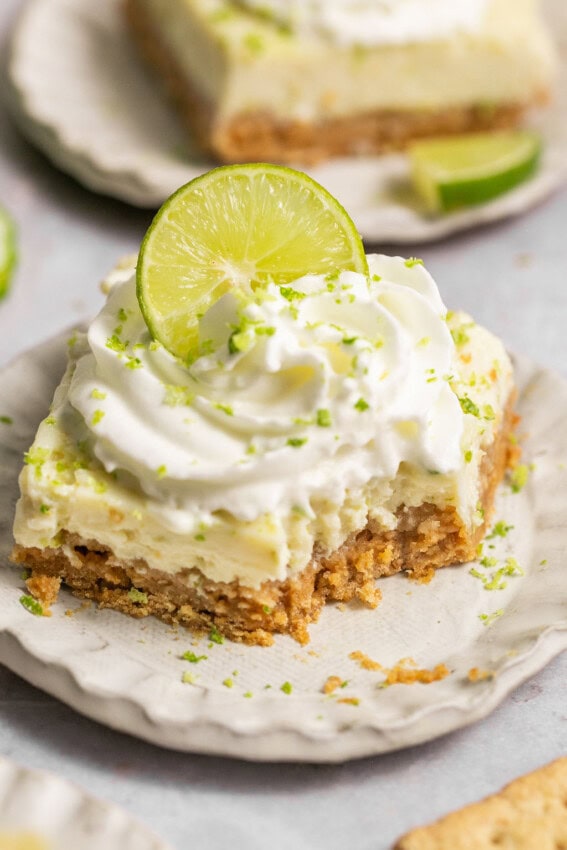 Key lime pie bar on a plate, missing a bite.