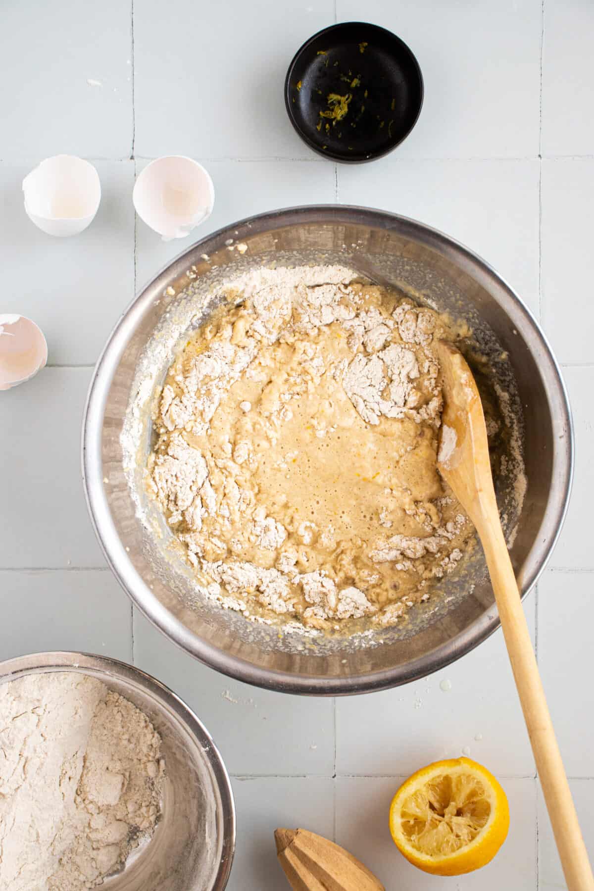 Wooden spoon stirring muffin batter in a bowl.