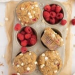 Raspberry white chocolate muffins in a muffin tin with raspberries.