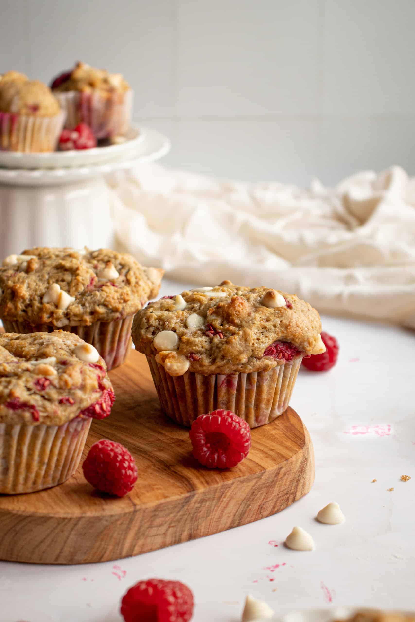 Raspberry white chocolate muffins on a wooden board.