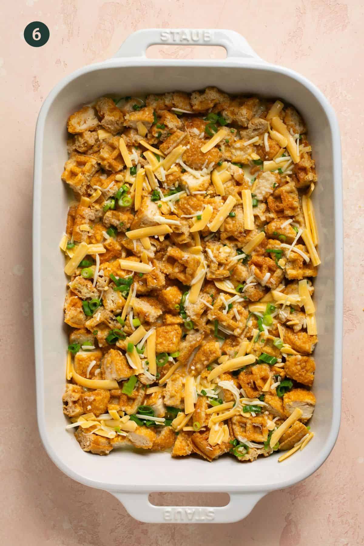 Chicken and waggles chopped covered with egg and cheese mixture in a casserole dish.