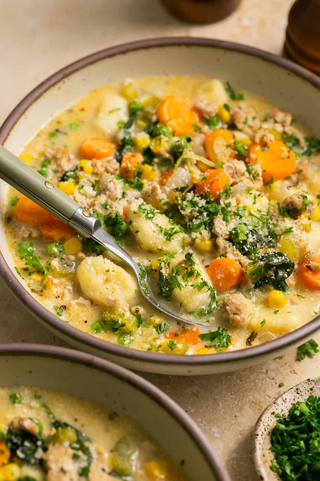 Soup in a bowl with parsley and cheese on top. 