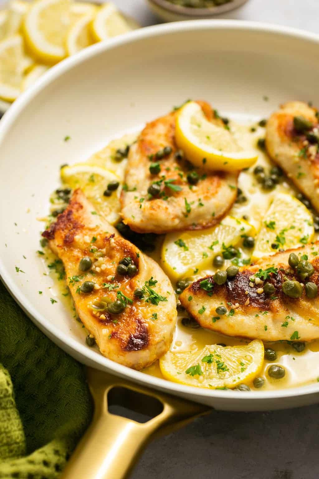 Chicken topped with capers and lemon slices.