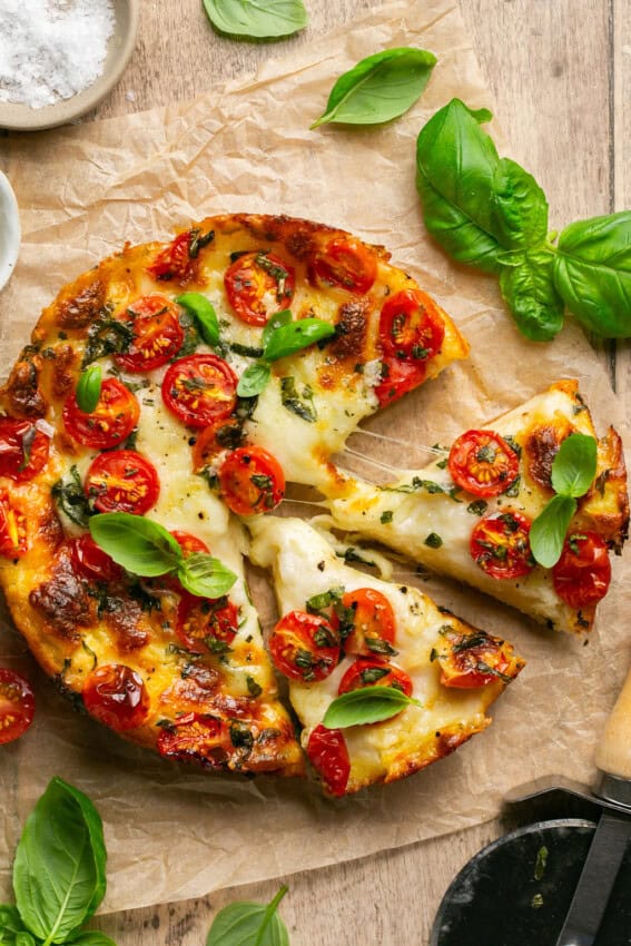 Partially-sliced Caprese Focaccia on parchment paper.