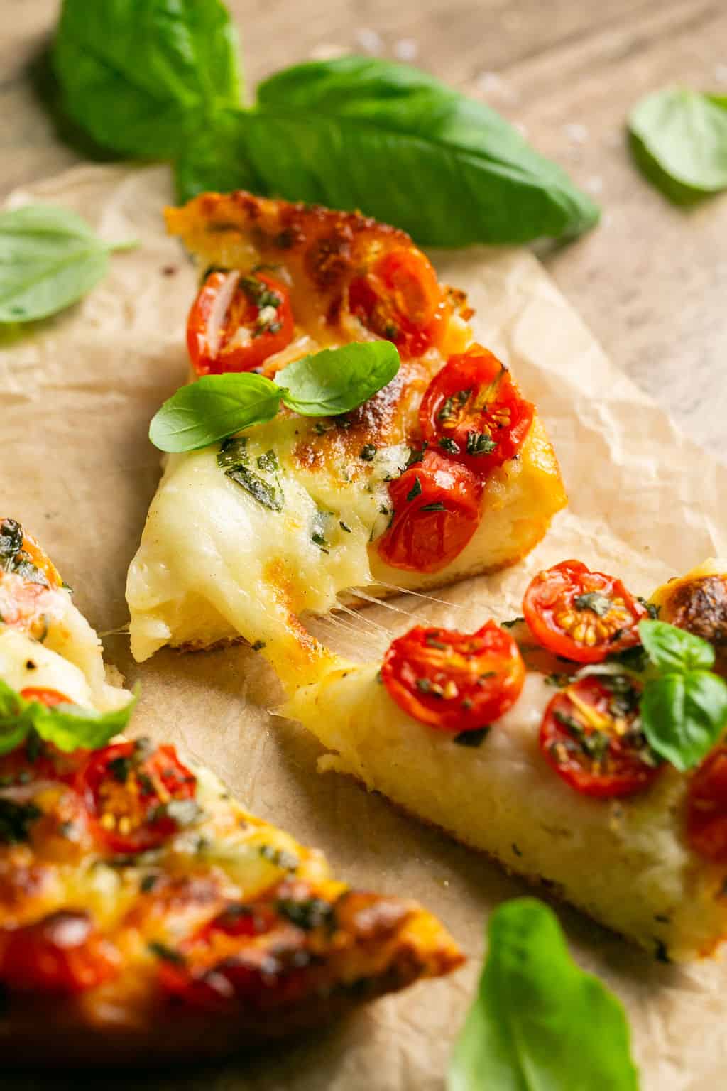 Slices of caprese focaccia with cherry tomatoes and basil.